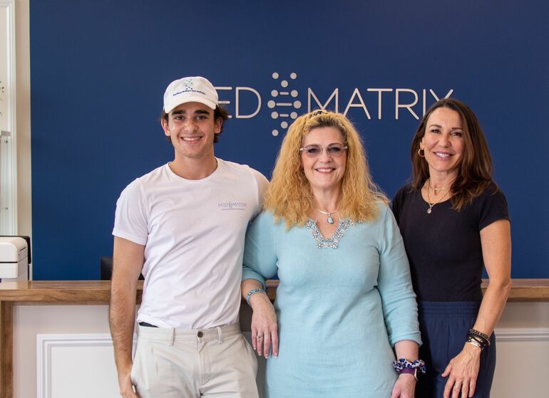 3 people smiling in front of sign