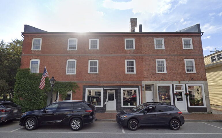 brick building with flag and 2 cars out front