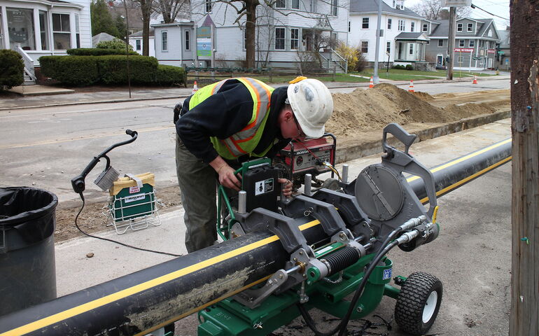 A Unitil employee works on a pipe.