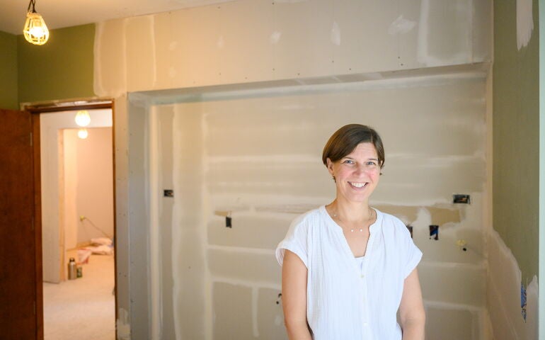 Liza Fleming-Ives with Genesis stands in a construction underway.