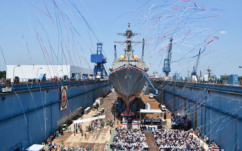 Aerial view of a ship in dry dock and lots of people and streamers.