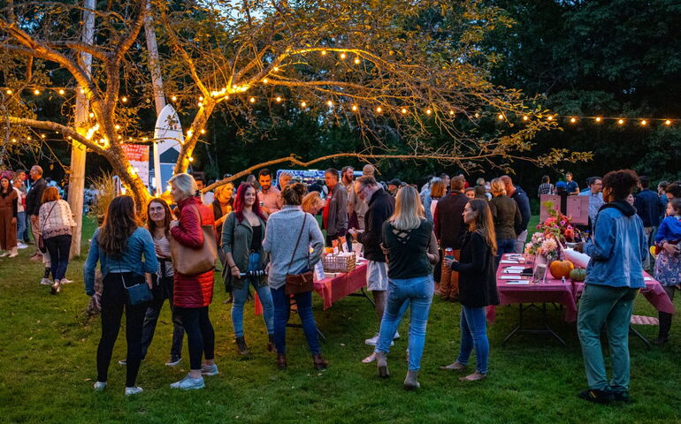 A crowd of people gather on a lawn for a Portside event.