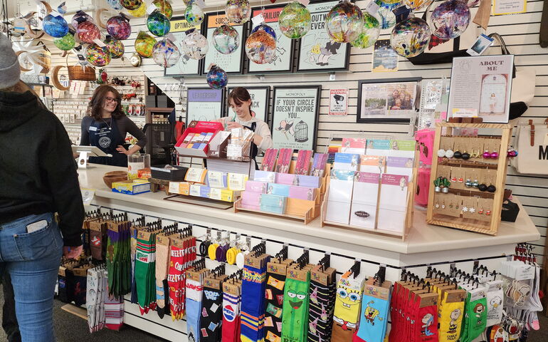 Clerks and a customer are inside a store with colorful products.