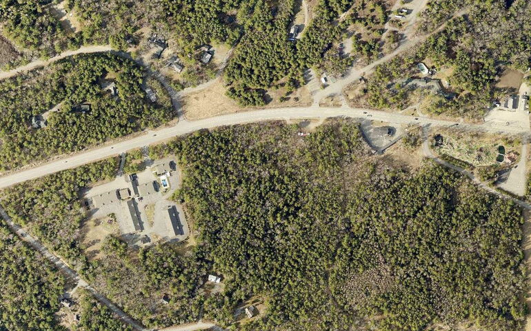 An aerial view shows woods and a road.