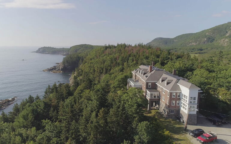 An aerial view shows a large building by the sea.