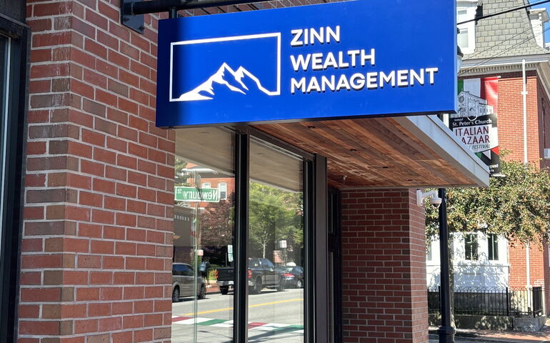 A brick building has big windows and a new blue sign.