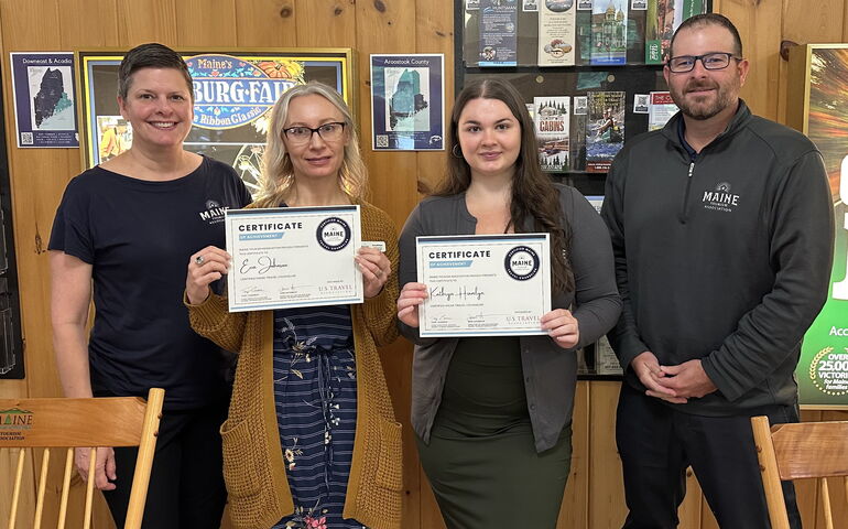 Four people pose with certificates at a travel center.