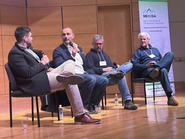 Four panelists on stage at a MEREDA event.