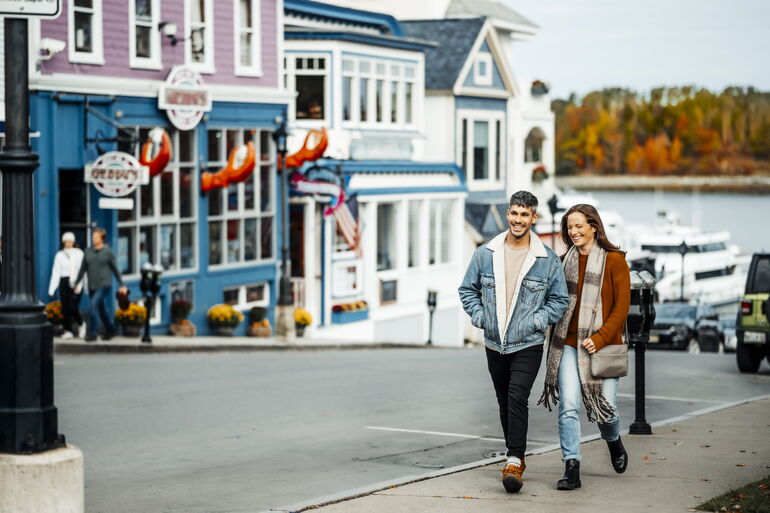 Couple walking in downtown Bar Harbor with shops in background.